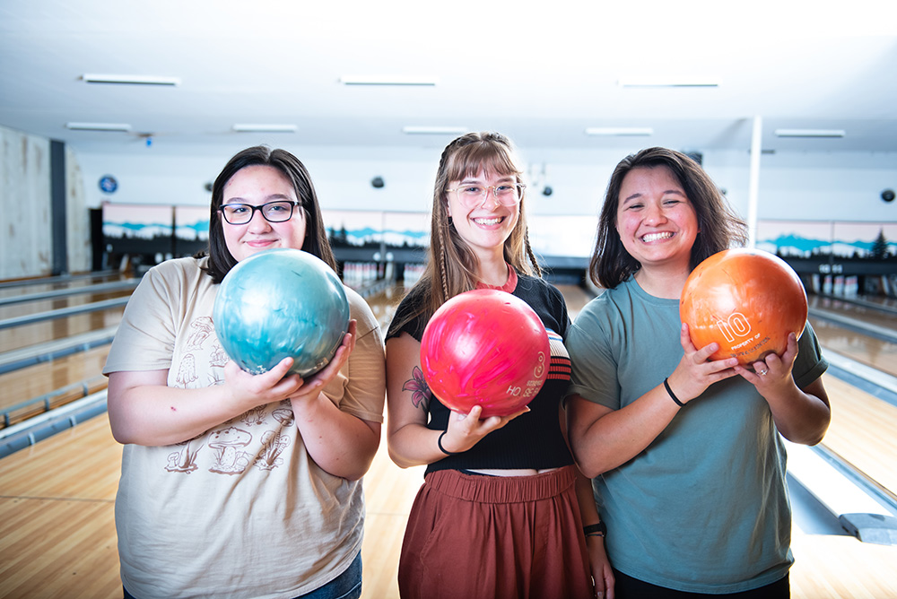Three teen girls holding bowling balls
